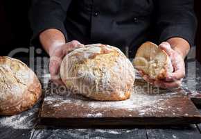 cook in a black tunic holds fresh baked bread