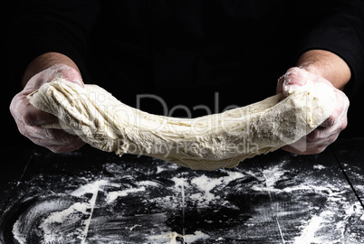 cook stretches kneaded dough from white wheat flour