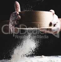 round wooden sieve with flour in male hands, the chef sifts whit