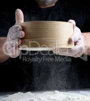 round wooden sieve in male hands