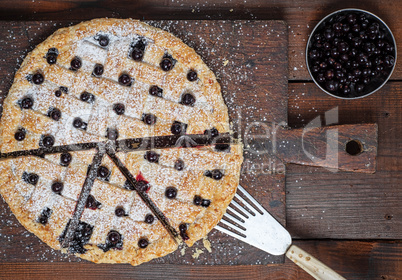baked round black currant cake on wooden background