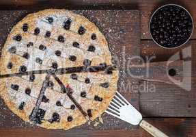 baked round black currant cake on wooden background