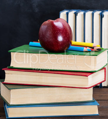 ripe red apple lying on a stack of books