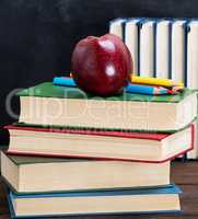 ripe red apple lying on a stack of books