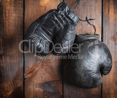 very old black boxing gloves on a brown wooden background