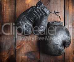 very old black boxing gloves on a brown wooden background