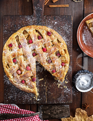 baked whole round apple pie on a rectangular old brown cutting b