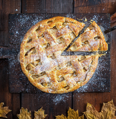 baked whole round apple pie on a rectangular old brown cutting b