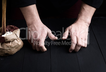two male hands over a black wooden table