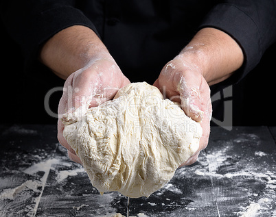 men's hands holding a ball of white yeast dough