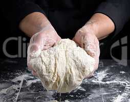 men's hands holding a ball of white yeast dough