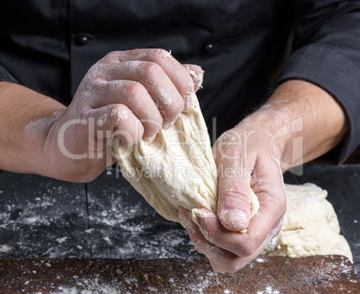 men's hands knead white wheat flour dough