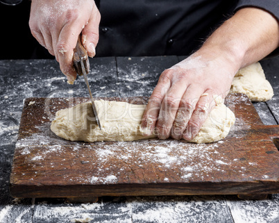 chef cuts white wheat flour dough into pieces