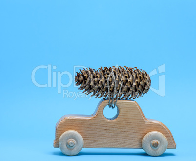 wooden toy car carries on top a pine cone on a blue background