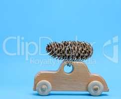 wooden toy car carries on top a pine cone on a blue background