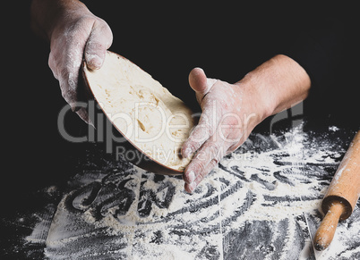 male hand holding a ceramic plate with yeast dough