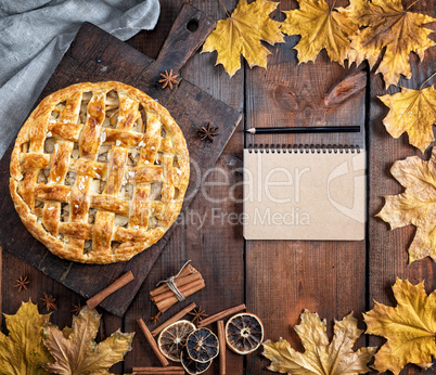 baked whole round apple pie on a brown wooden board, puff pastry
