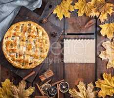 baked whole round apple pie on a brown wooden board, puff pastry