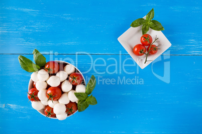 Mozzarella, cherry tomatoes and basil in a bowl seen from above