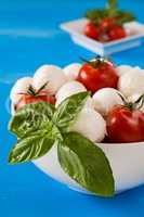 Closeup of fresh mozzarella, cherry tomatoes and basil in a bowl