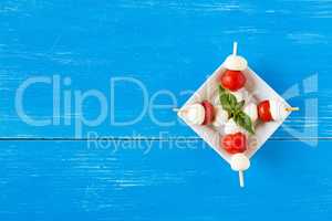 Skewers with mozzarella, cherry tomatoes and basil seen from abo