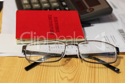 Bill for payment, glasses, calculator on the surface of the table. translation of the inscription: the identity of the pensioner