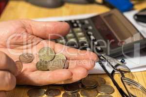 Hand pensioner, glasses, calculator and coins on the table surface. translation of the inscription: the identity of the pensioner