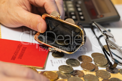 Hand pensioner, glasses, calculator and wallet with coins on the surface of the table. Translation of the inscription: "pensioner's Certificate"