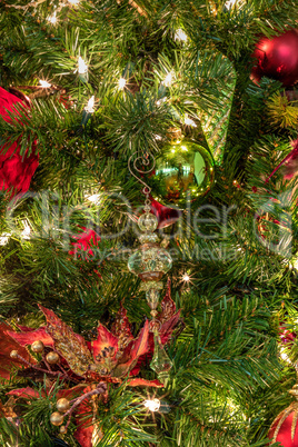 Red and green ornaments on a Christmas tree with white lights