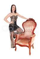 Lovely woman standing behind an old armchair in a dress