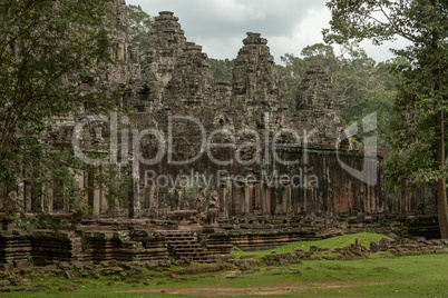 Facade of Bayon temple surrounded by trees