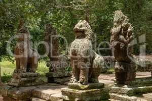 Four lion and snake statues in forest