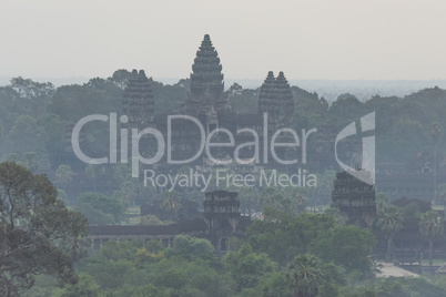 Misty ruins of Angkor Wat among trees