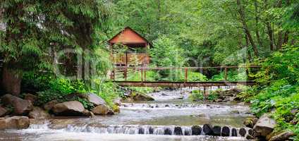 Mountain river, lush vegetation and recreation area with a bridg