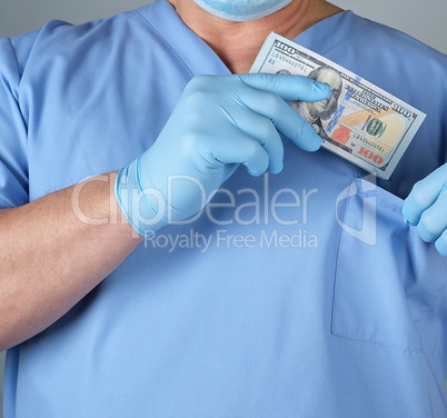 male doctor puts a wad of dollars in his shirt pocket