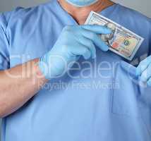 male doctor puts a wad of dollars in his shirt pocket