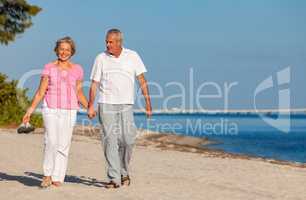 Happy Senior Couple Walking Holding Hands on a Beach