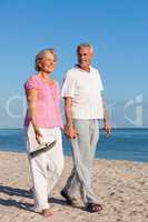 Happy Senior Couple Walking Holding Hands on a Beach