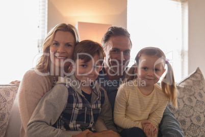 Happy family sitting together on sofa in living room at home