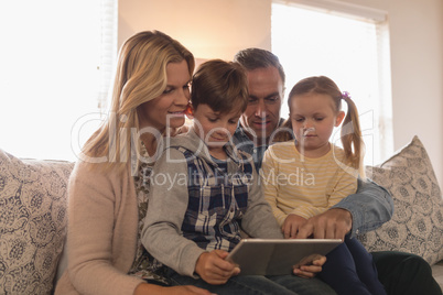 Family using digital tablet together in living room