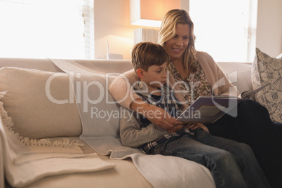 Mother with her son reading story book in living room