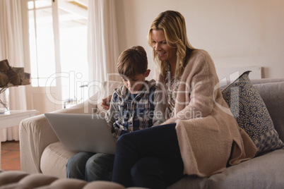 Mother with her son using laptop in living room