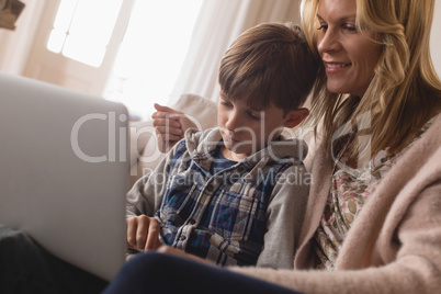 Mother with her son using laptop in living room