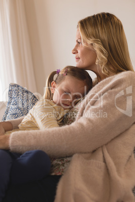 Mother embracing her sleeping daughter in arms