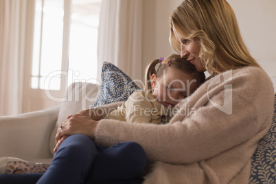 Mother embracing her sleeping daughter in arms
