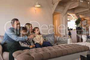 Family watching television in living room at home