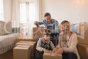 Family unpacking cardboard boxes in their new home