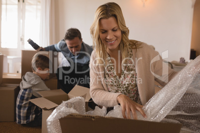 Family unpacking cardboard boxes in their new home