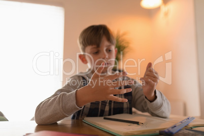 Boy counting on fingers while doing his homework
