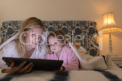 Mother and daughter using digital tablet in bedroom